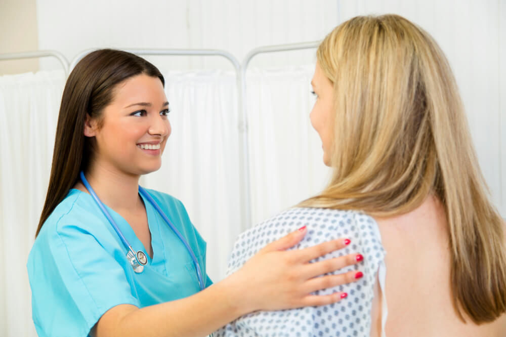 A nurse speaking with a female patient who is undergoing a breast exam/mammogram.