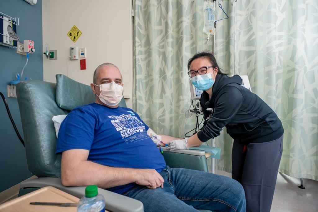 Outpatient CAR T-cell therapy patient Alan Morris during infusion at Dana-Farber with Grace Liu, BSN, RN, working on the infusion pump.