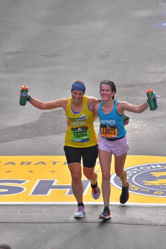 Anne Keane (left) crosses the finish line of the 2021 Boston Marathon with friend Lynn Reisman. 