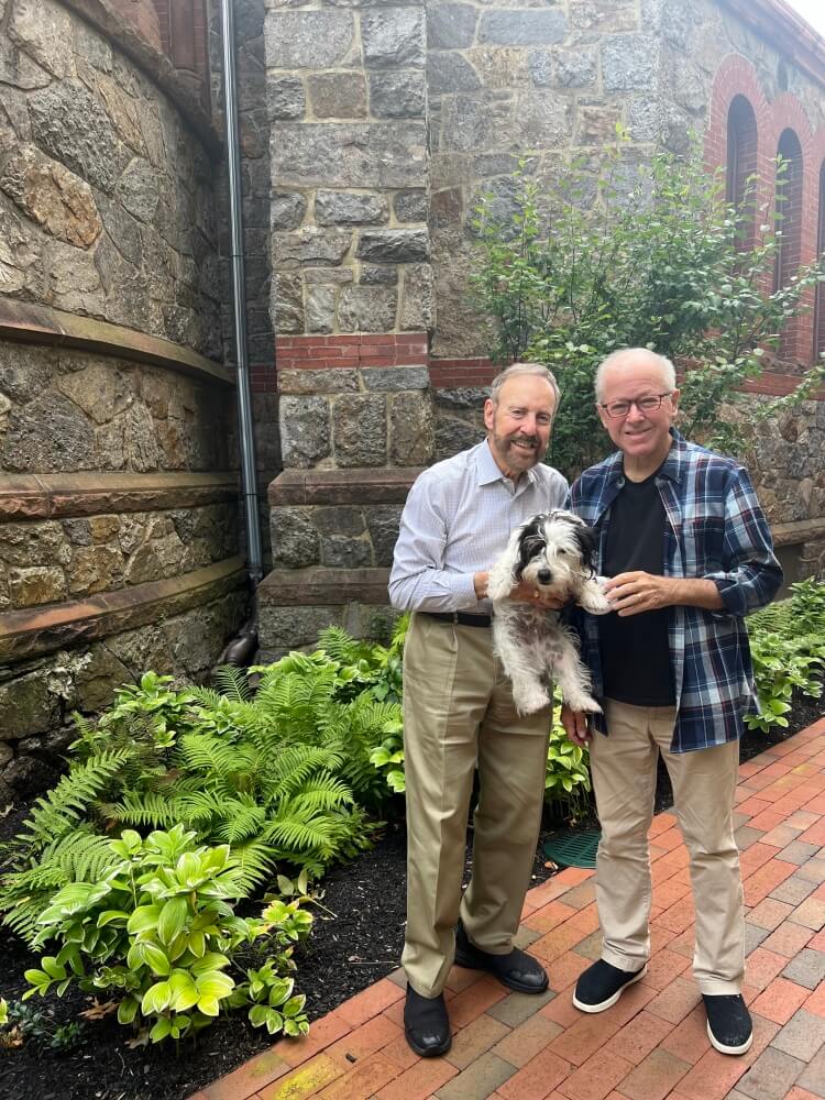Trueblood (right) takes daily walks around Cambridge post-transplant, here joined by his husband, Michael Flier, and their Sealyham terrier, Edgar, outside St. James Church.