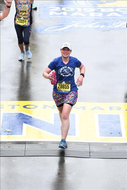 Meghan MacDonald running across  the Boston Marathon finish line.